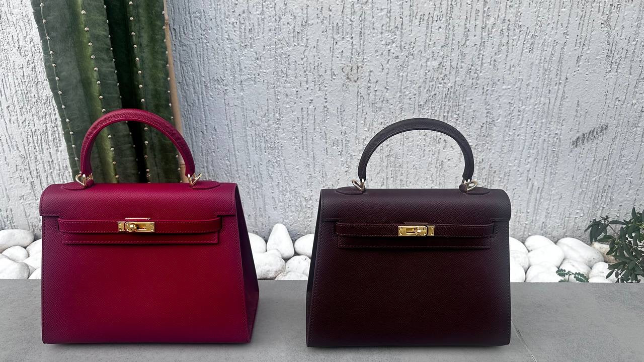 Two handbags, one red and one brown, on a textured surface with decorative elements.