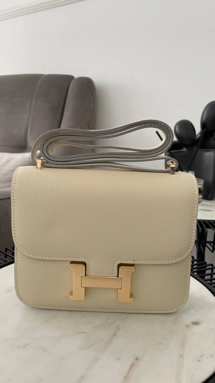 Beige handbag with gold clasp on a marble surface