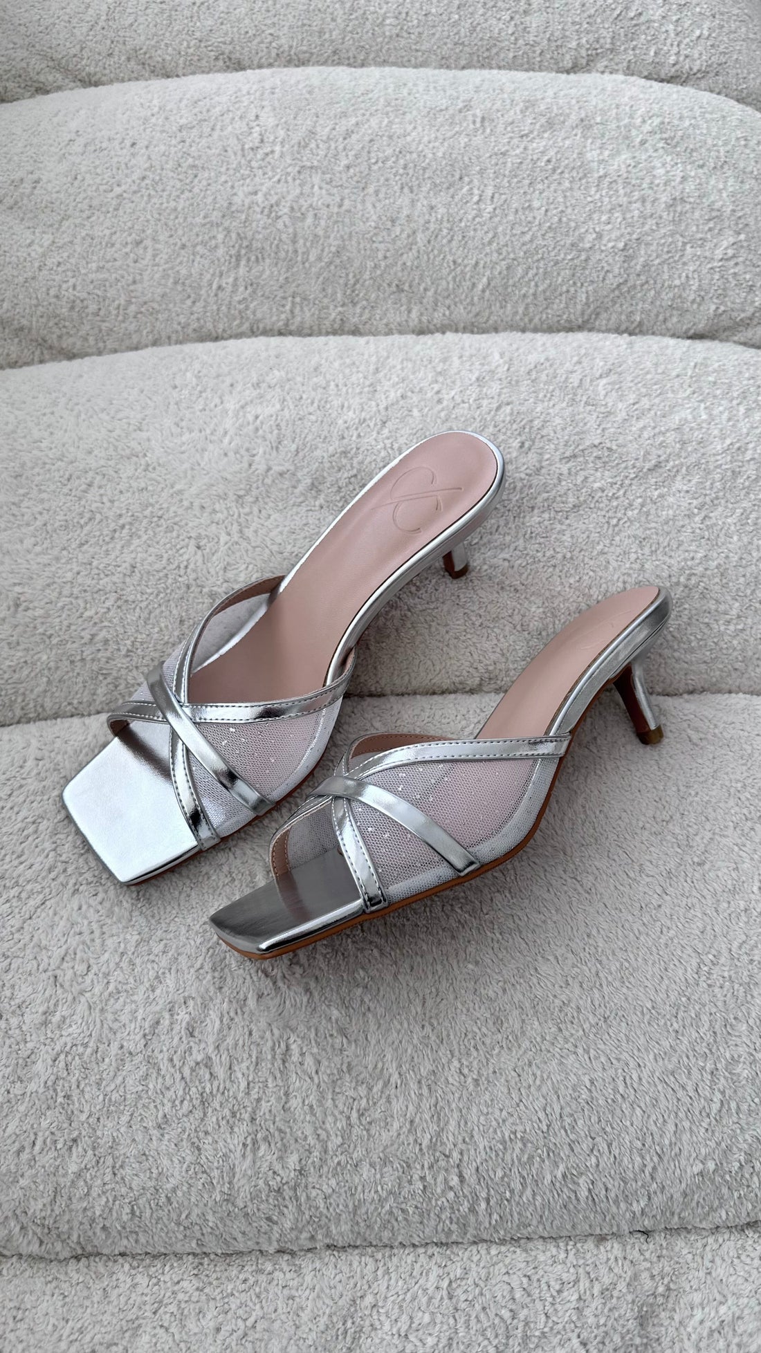 Silver high-heeled sandals on a light gray surface