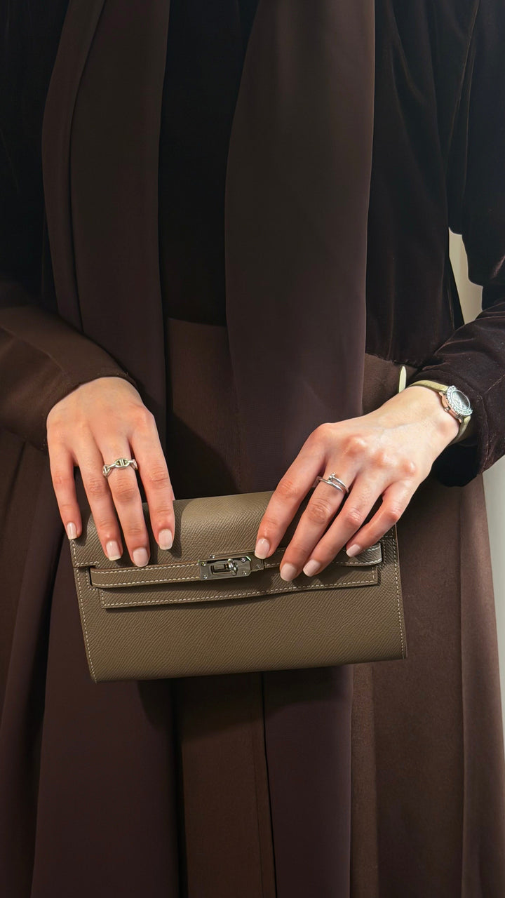 Person holding a green clutch with a plain background