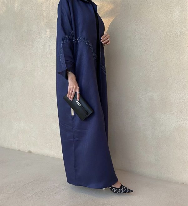 Person wearing a long navy blue dress with a plain background