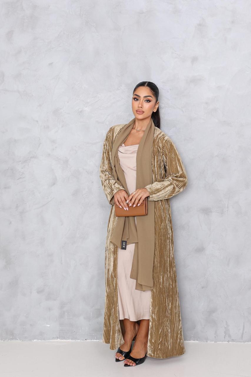 Woman wearing a long beige coat over a white dress against a light gray background