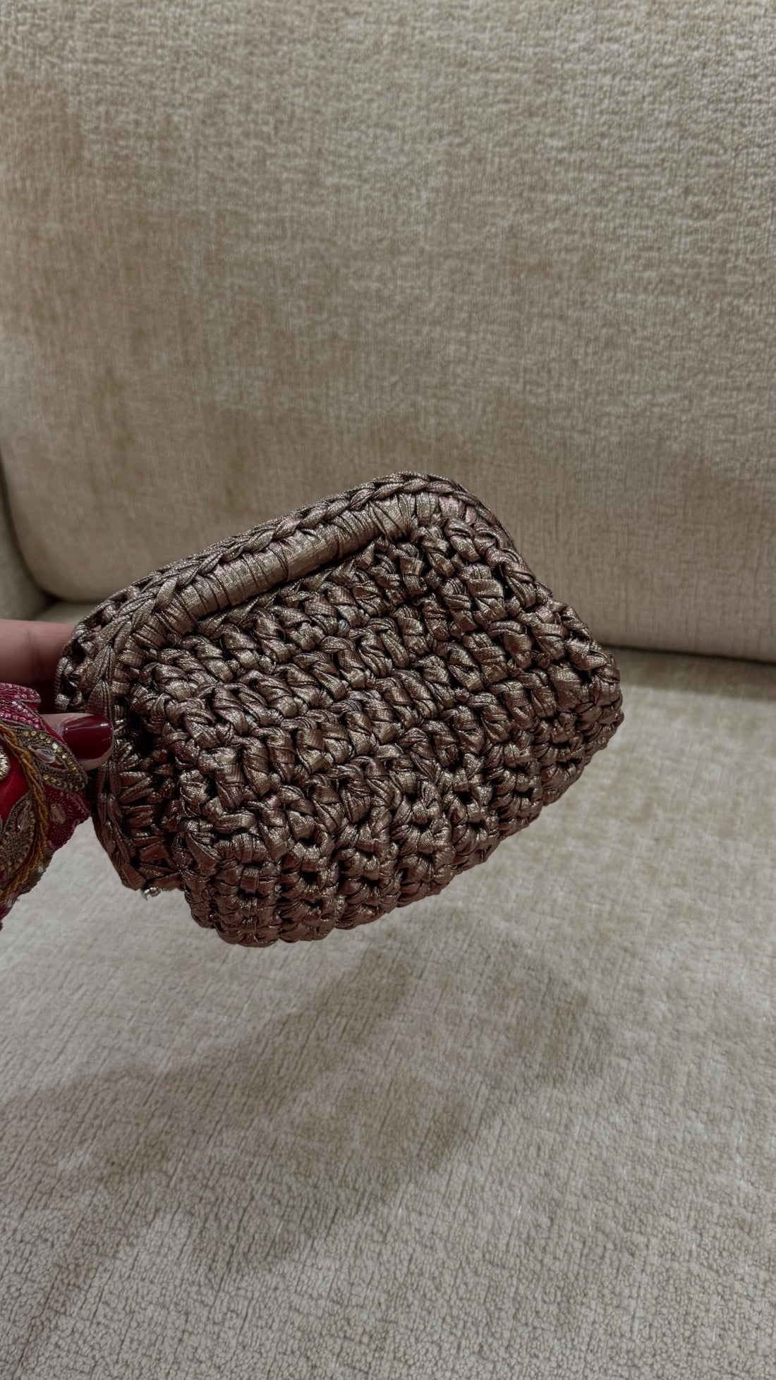 Brown woven pouch held against a beige sofa background