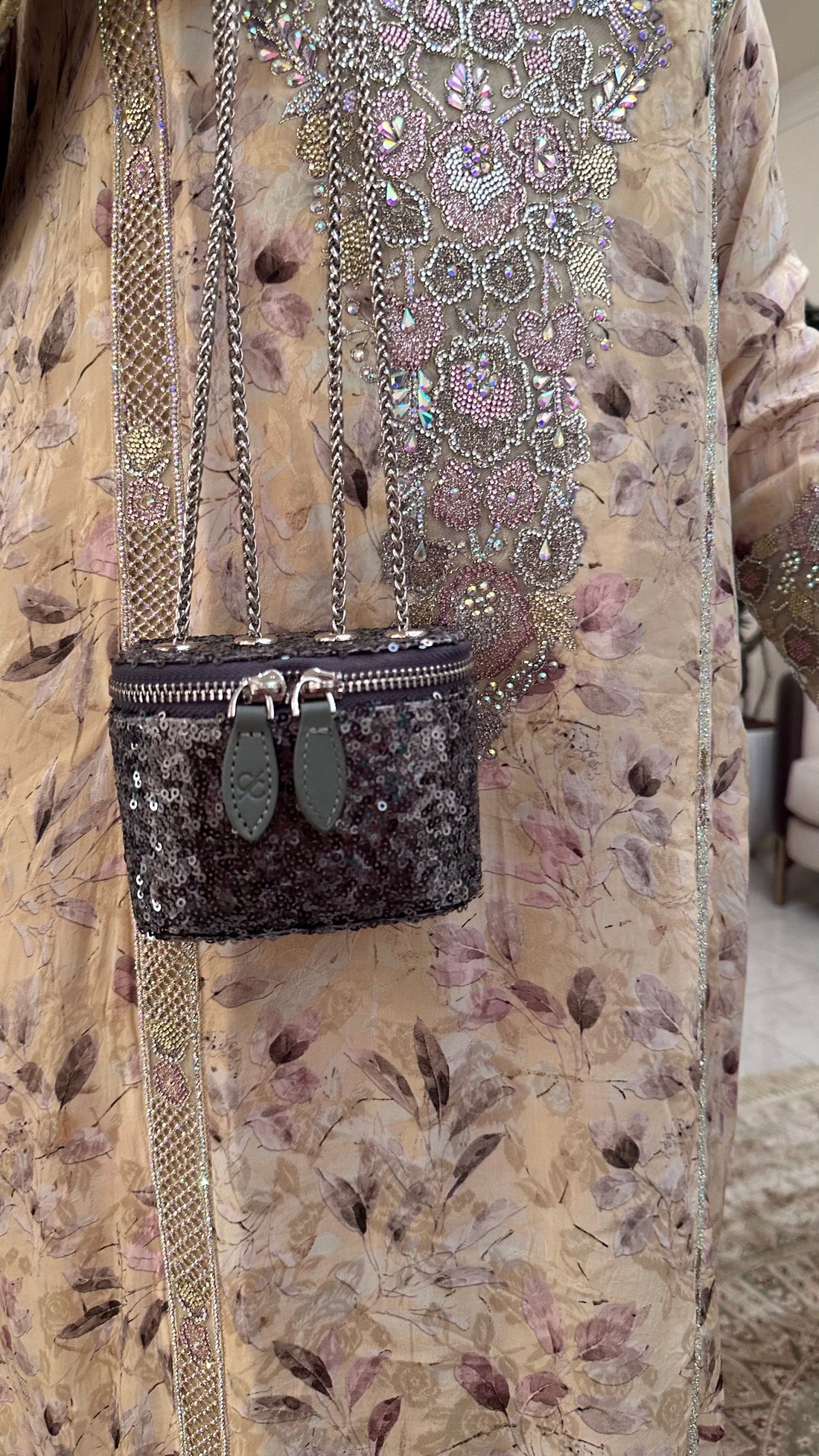 Black sequined handbag with green accents on a floral dress
