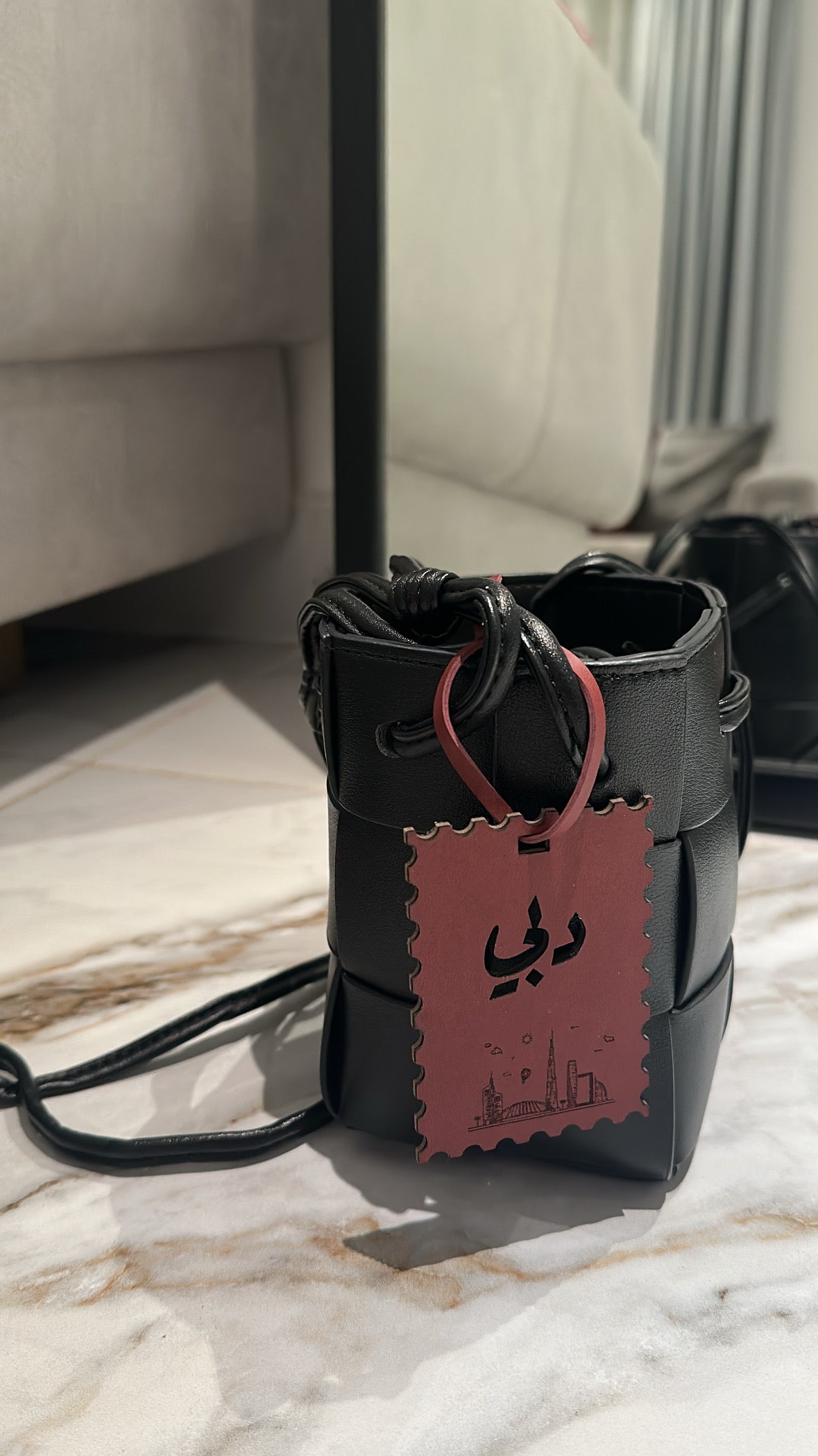 Black leather bag with a pink tag on a marble surface