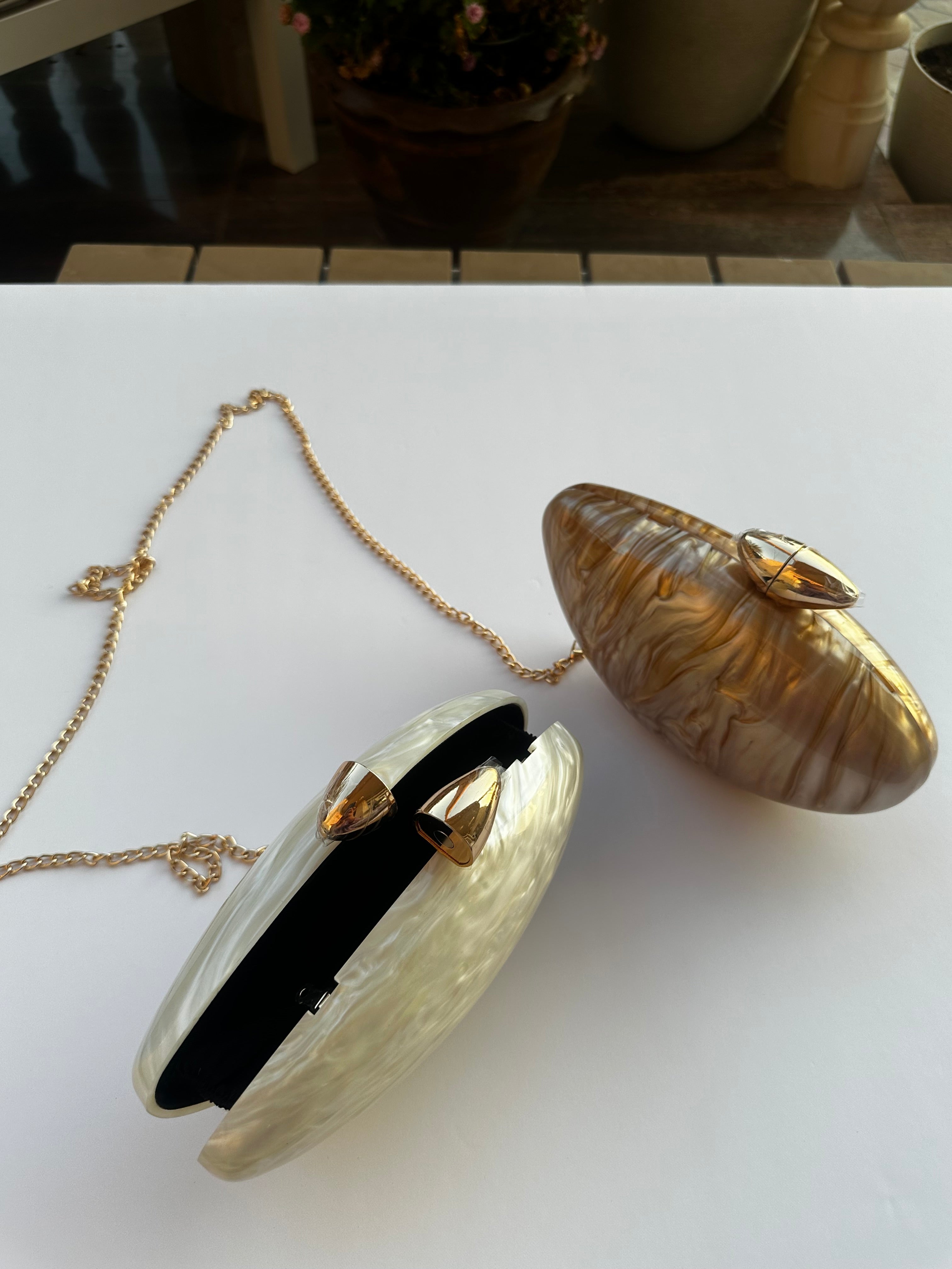 Gold shell-shaped clutch with a chain on a white surface