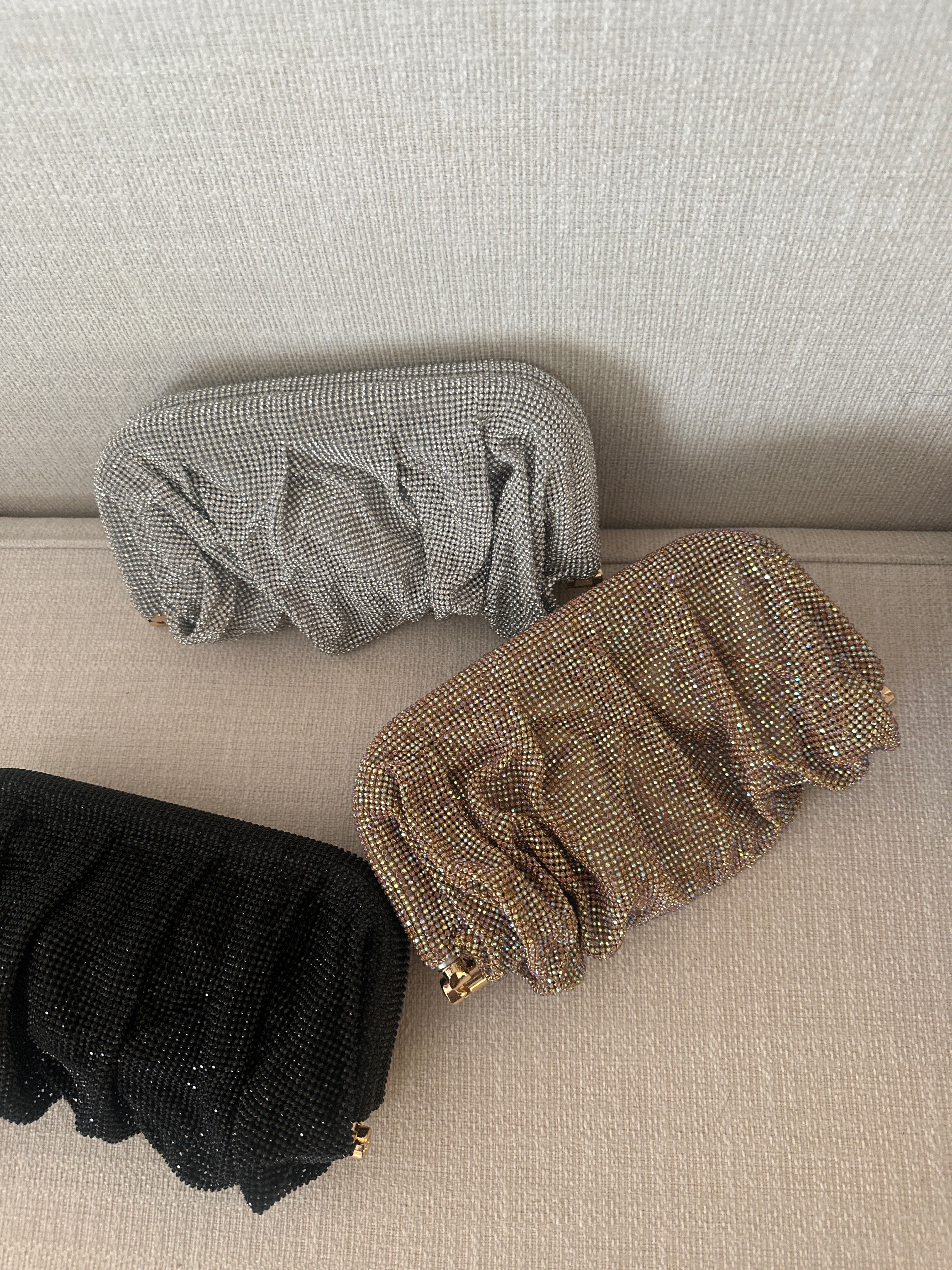 Three pairs of glittery socks in black, gold, and gray on a beige surface.