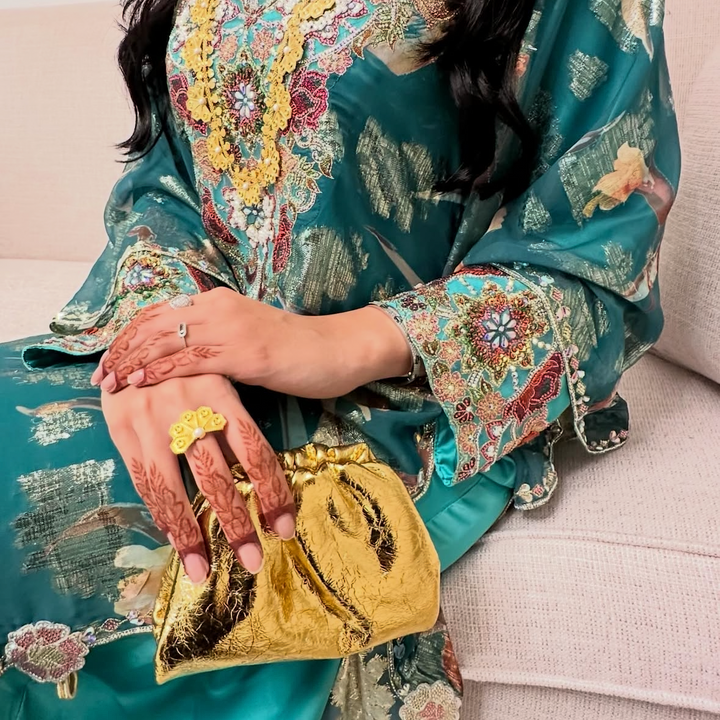 Person wearing a floral dress with gold accents sitting on a couch.