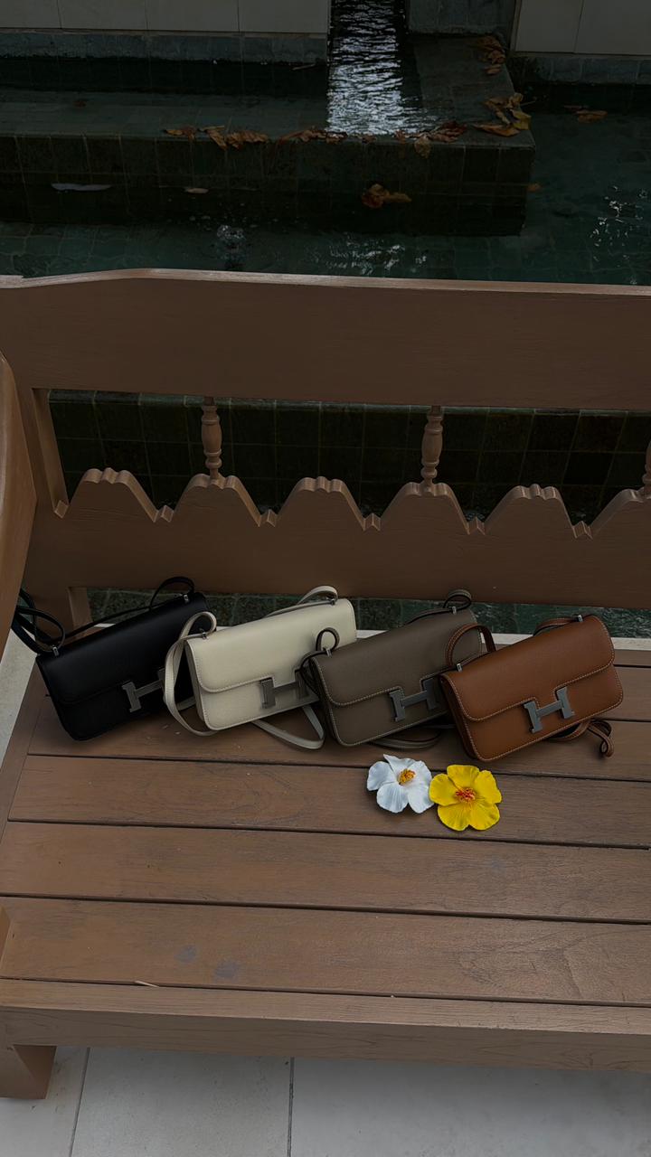 Row of handbags on a wooden bench with flowers nearby