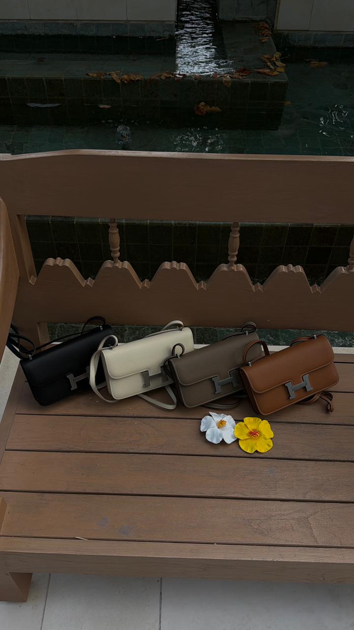 Collection of handbags on a wooden bench with flowers nearby