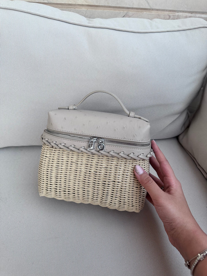 Hand holding a wicker basket with a beige lid on a light-colored couch.