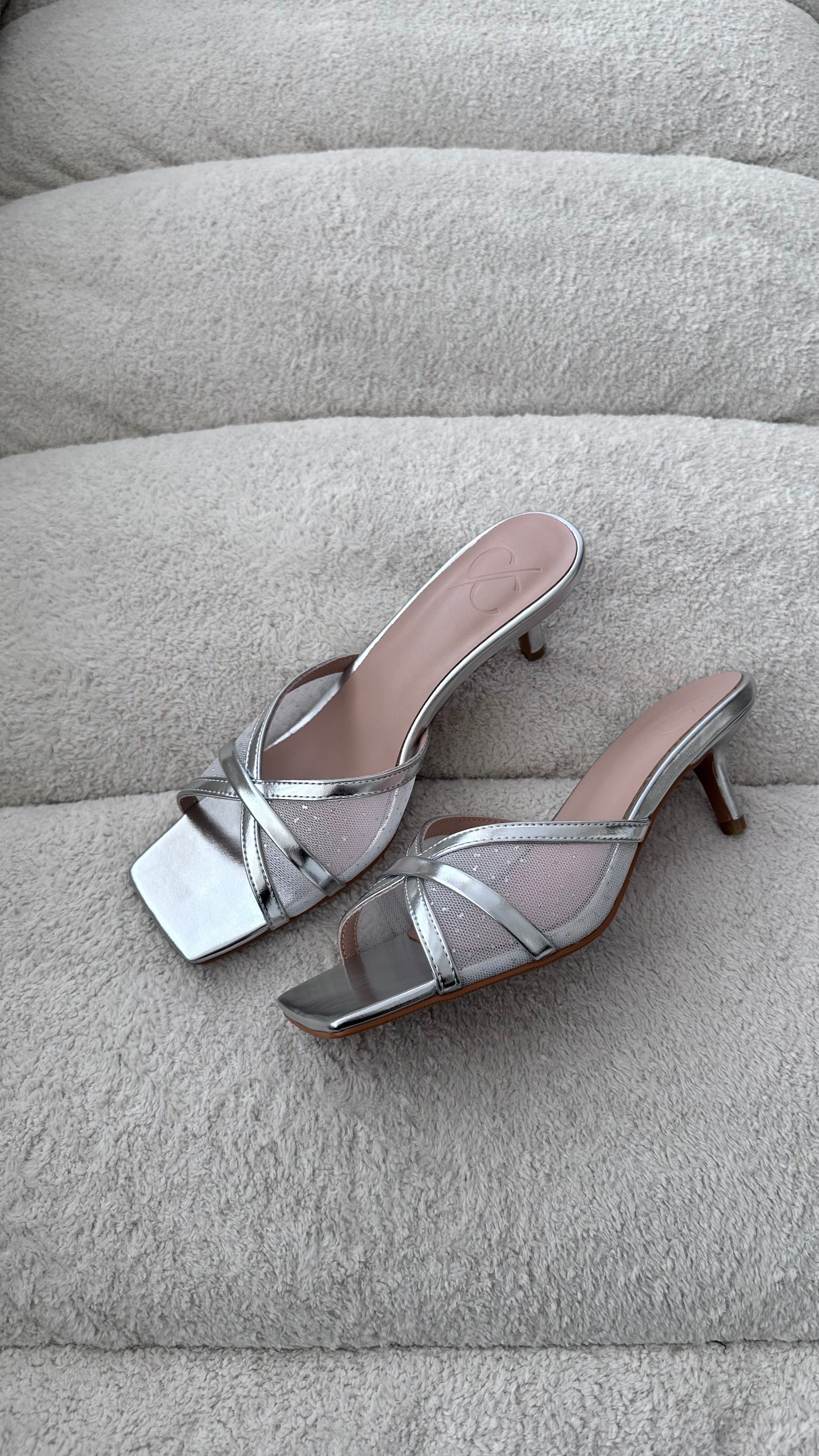 Silver high-heeled sandals on a textured gray surface