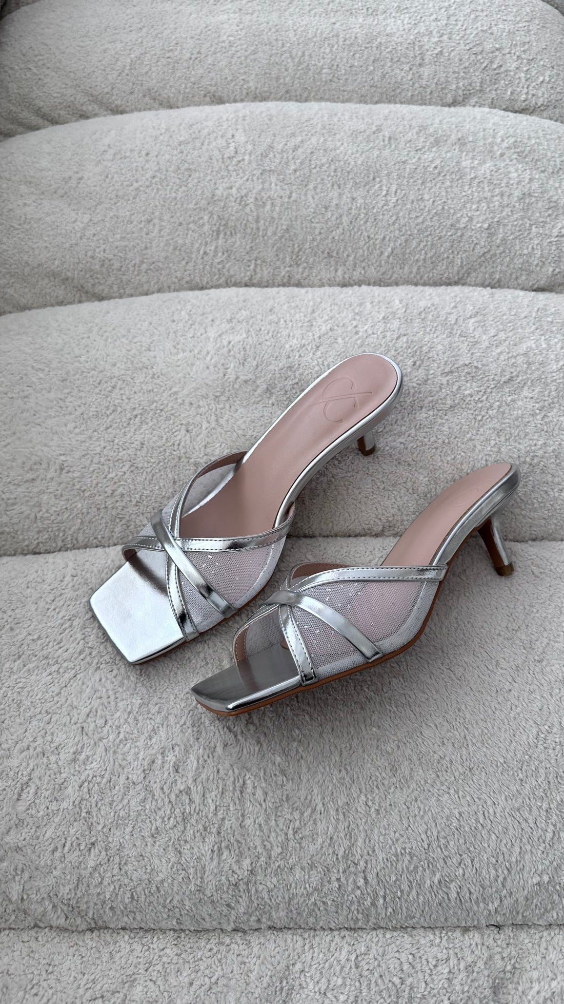 Silver high-heeled sandals on a textured gray surface