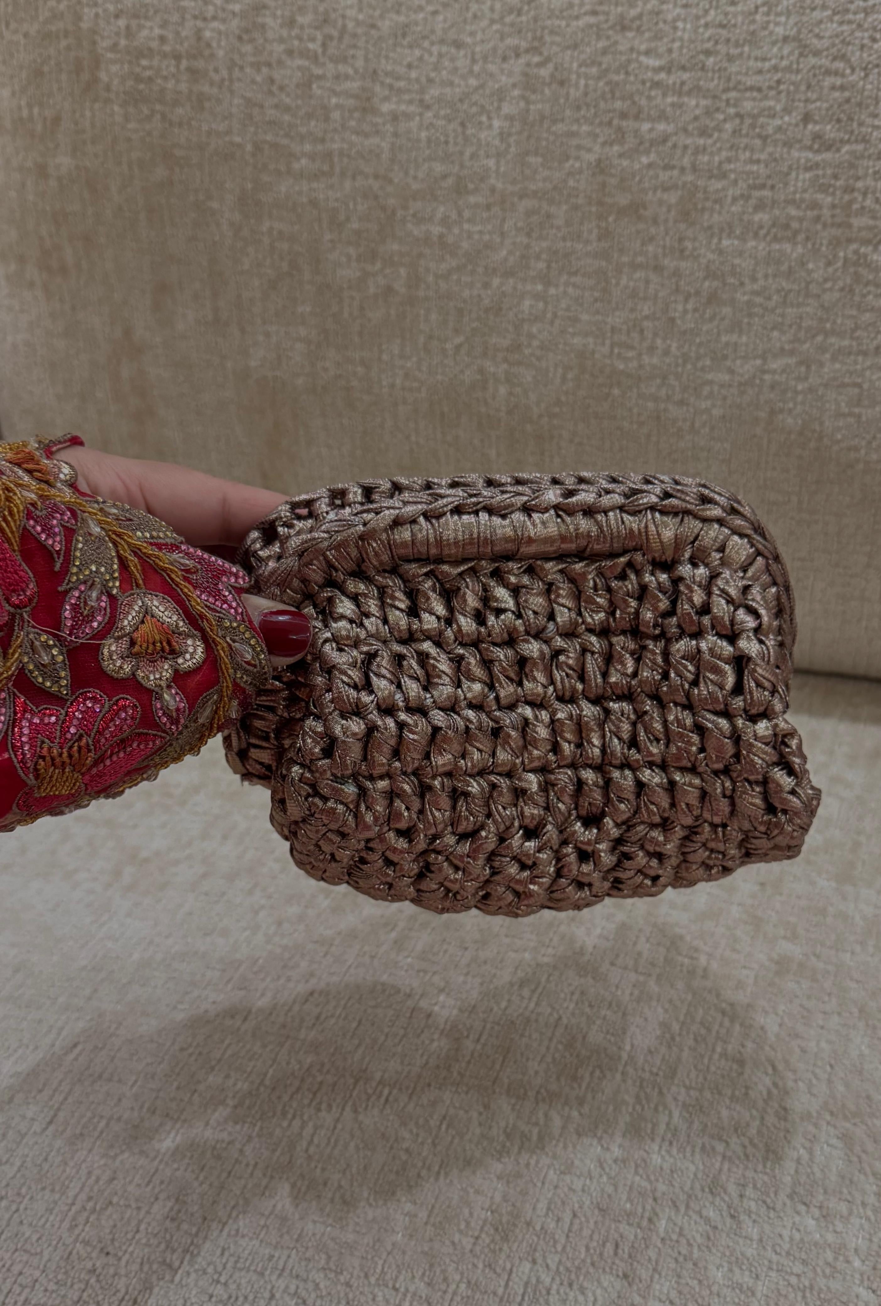 Brown woven clutch bag held by a person with a beige background