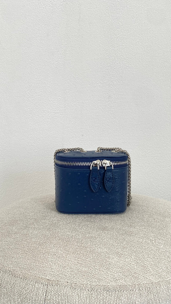 Blue handbag with chain detail on a light gray surface