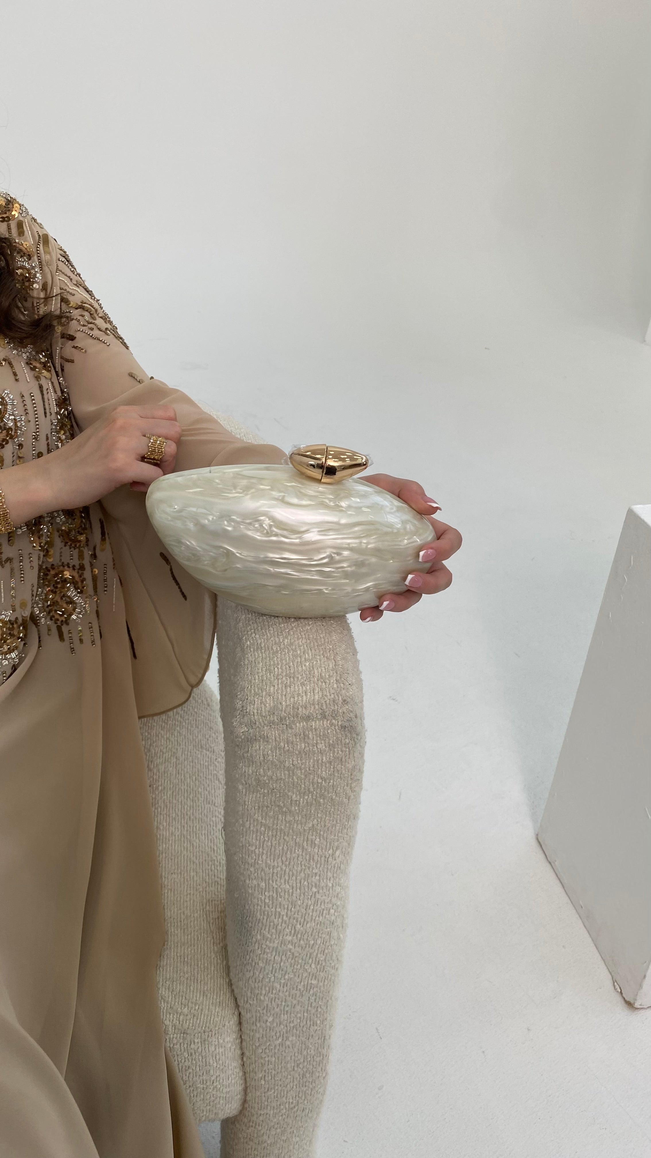 Person holding a textured clutch bag against a plain background