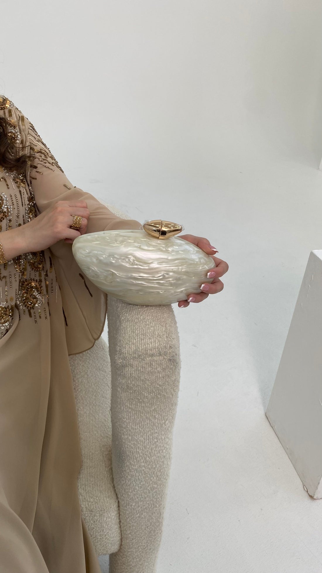Person holding a textured clutch bag against a plain background