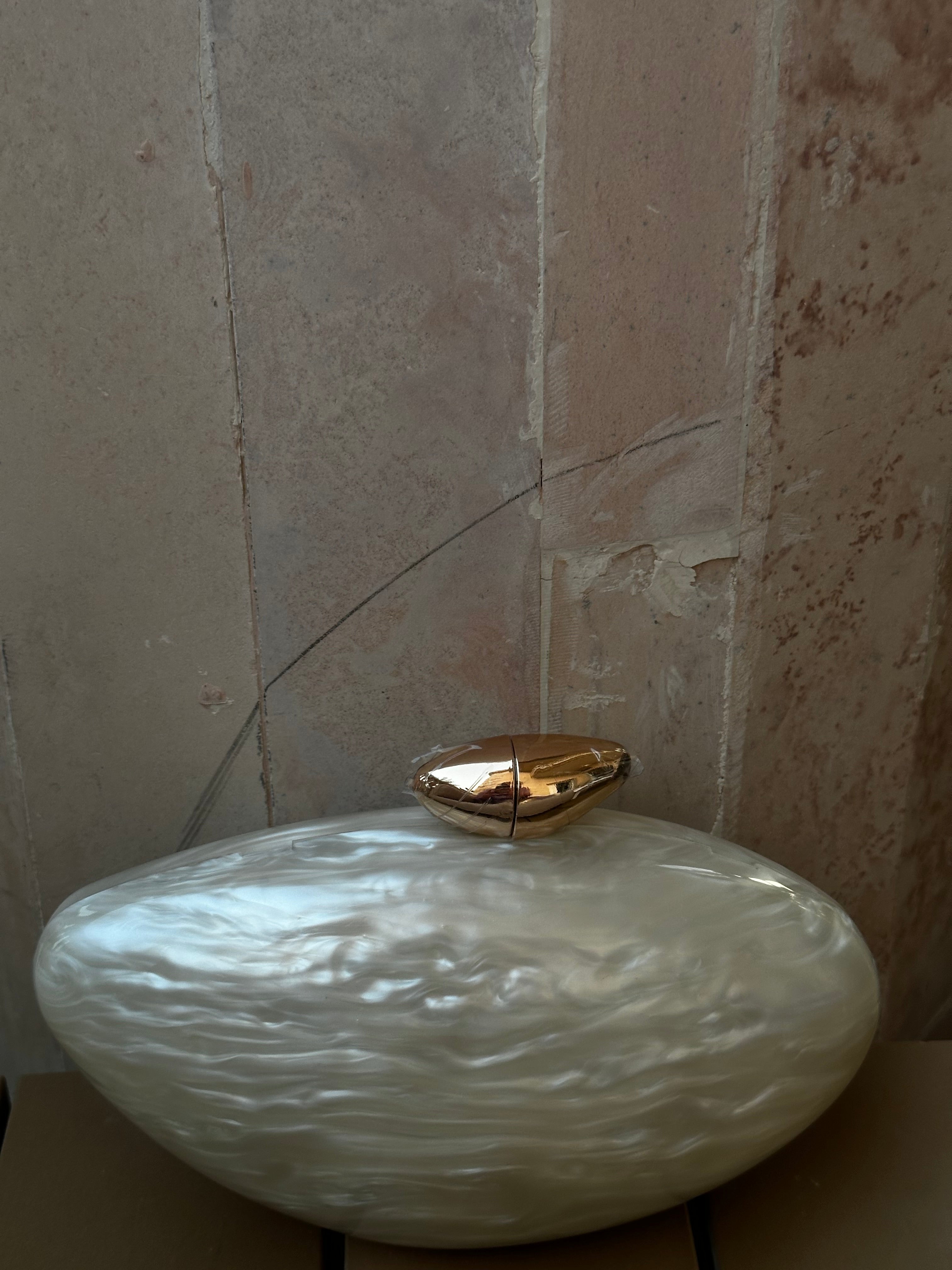 White textured vase with a gold lid on a neutral background