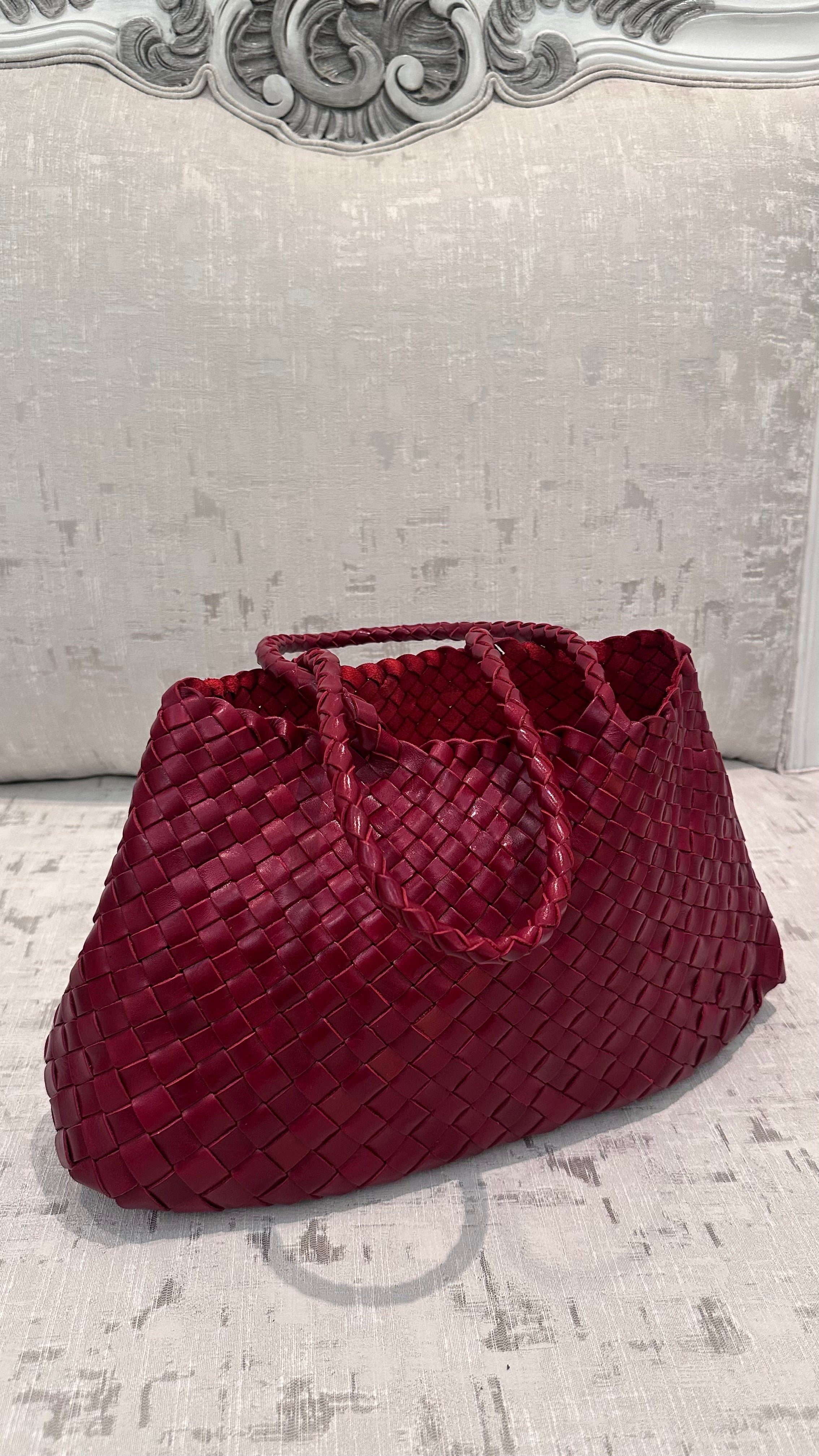 Red woven handbag on a textured surface with decorative wall in the background