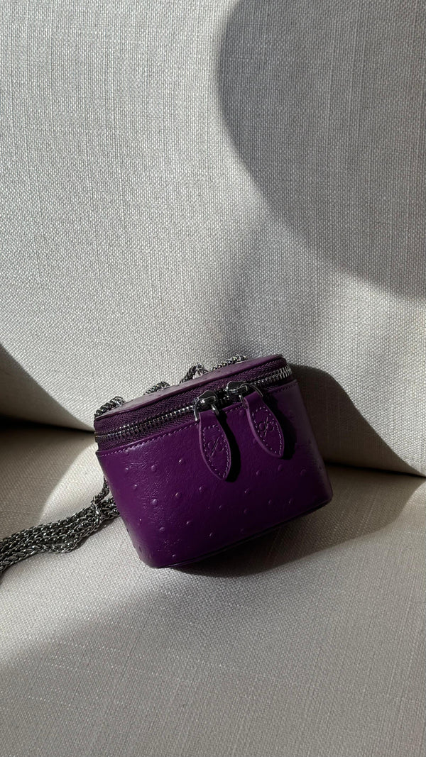 Purple handbag with chain detail on a light gray background