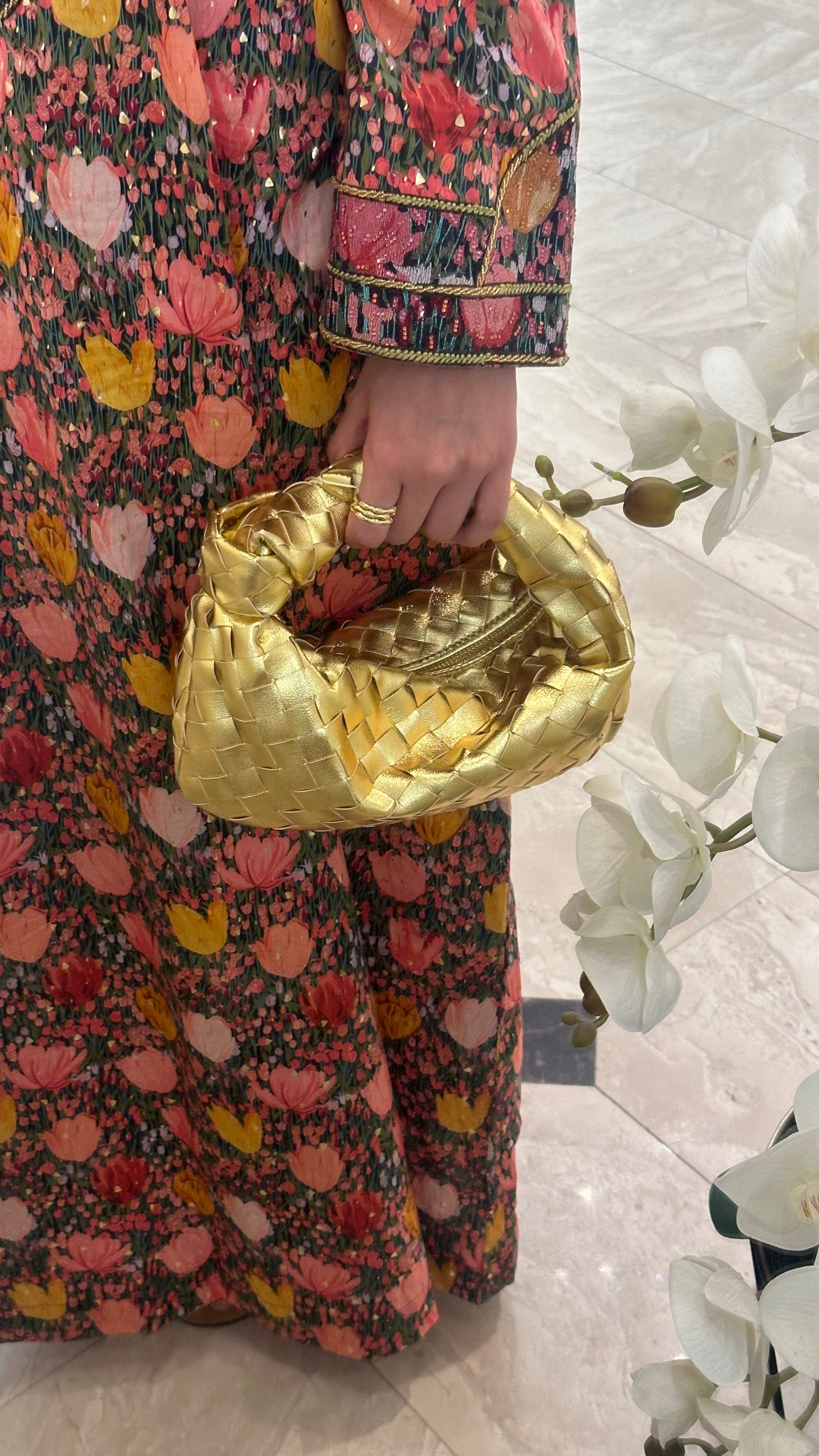 A person holding a gold leather shoulder bag.
