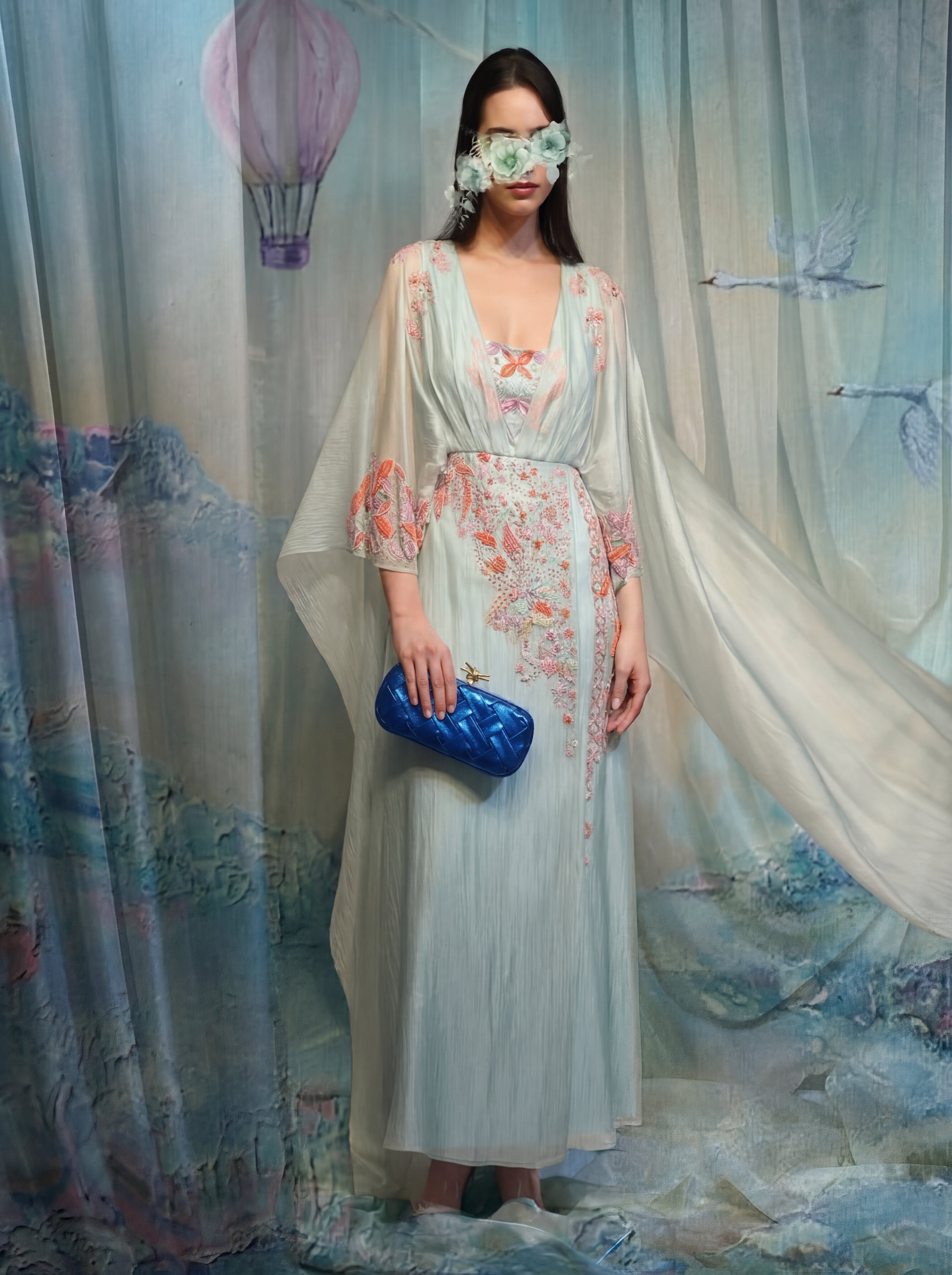 Woman in a floral dress with a blue clutch against a dreamy, artistic background