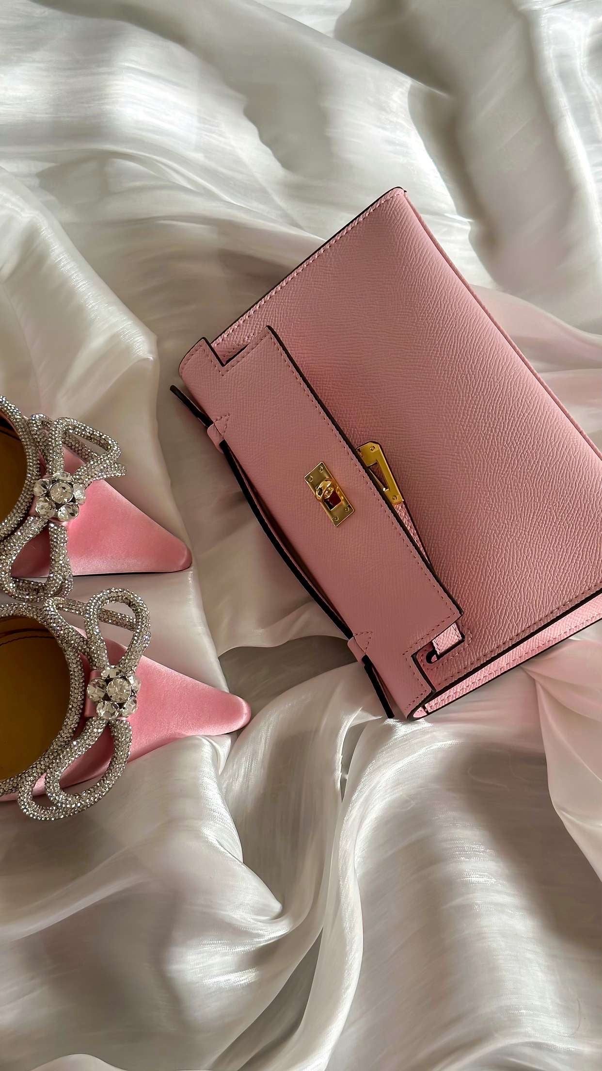 Pink handbag with decorative elements on a white fabric background