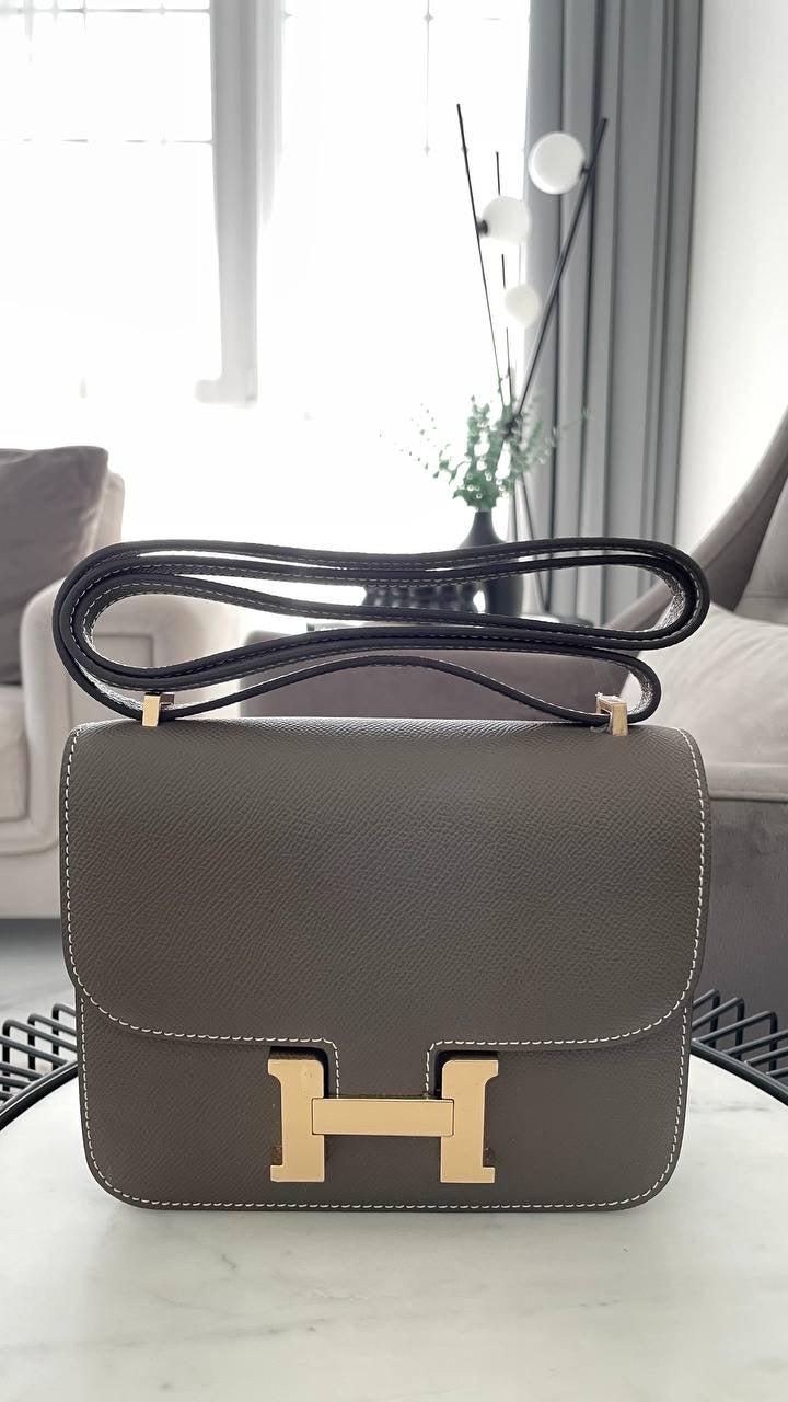 Gray handbag with gold hardware on a white surface
