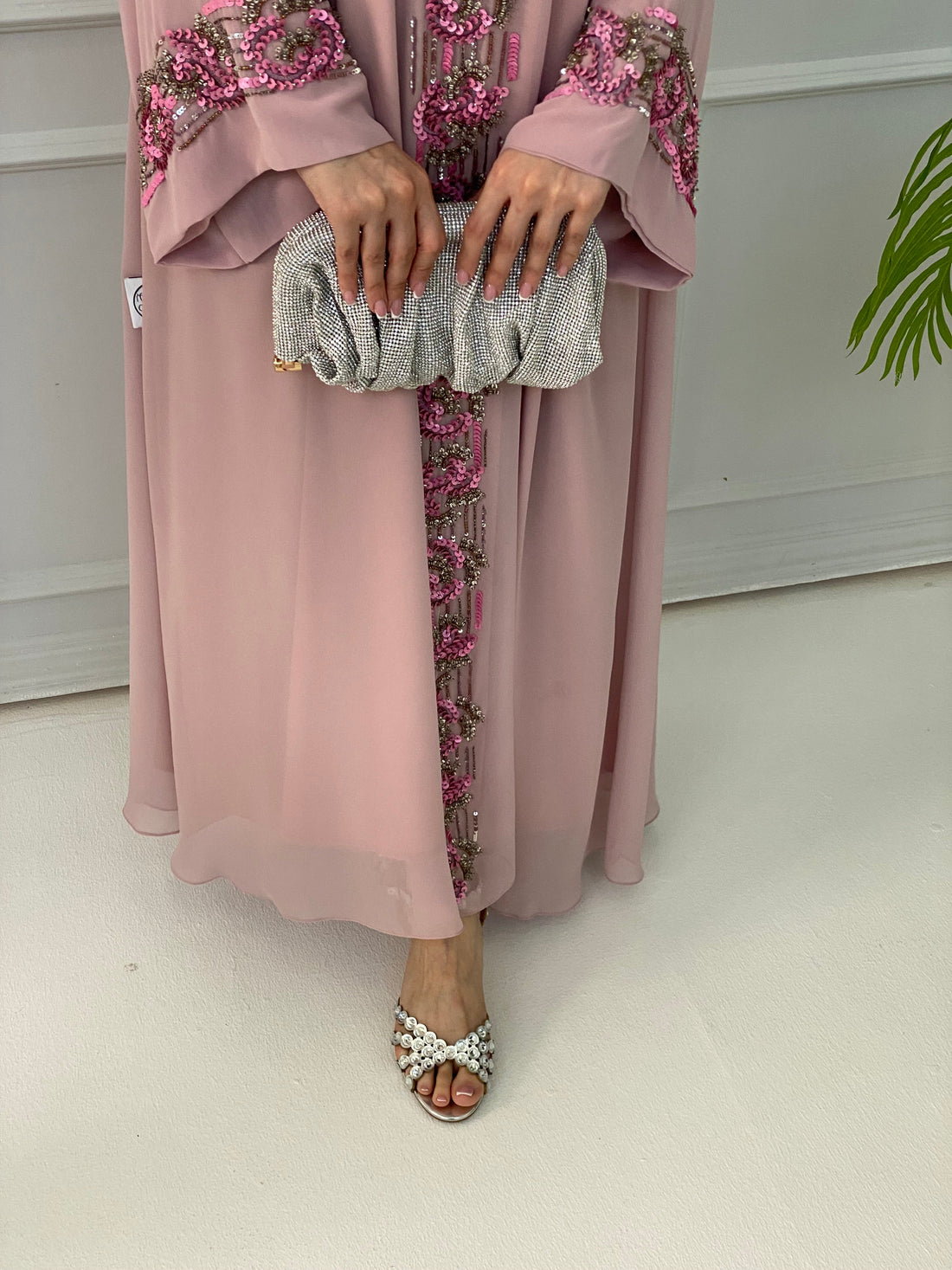 Person wearing a pink dress with floral patterns and holding a clutch.