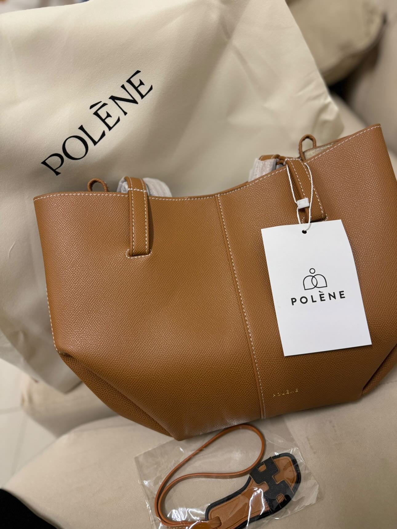 A brown leather handbag with the Polene brand tag visible, displayed against a neutral background.