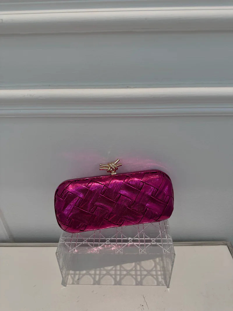 Pink clutch bag on a clear stand against a white background