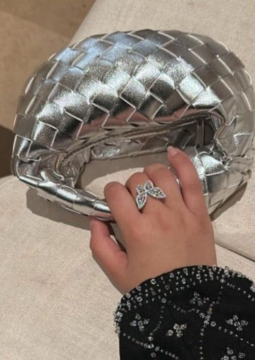 A person's hand holding a silver micro handle bag.