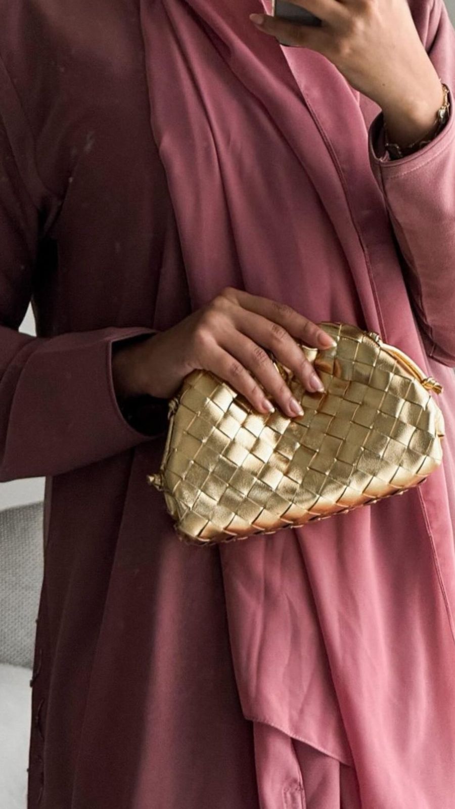 Person holding a gold woven clutch bag