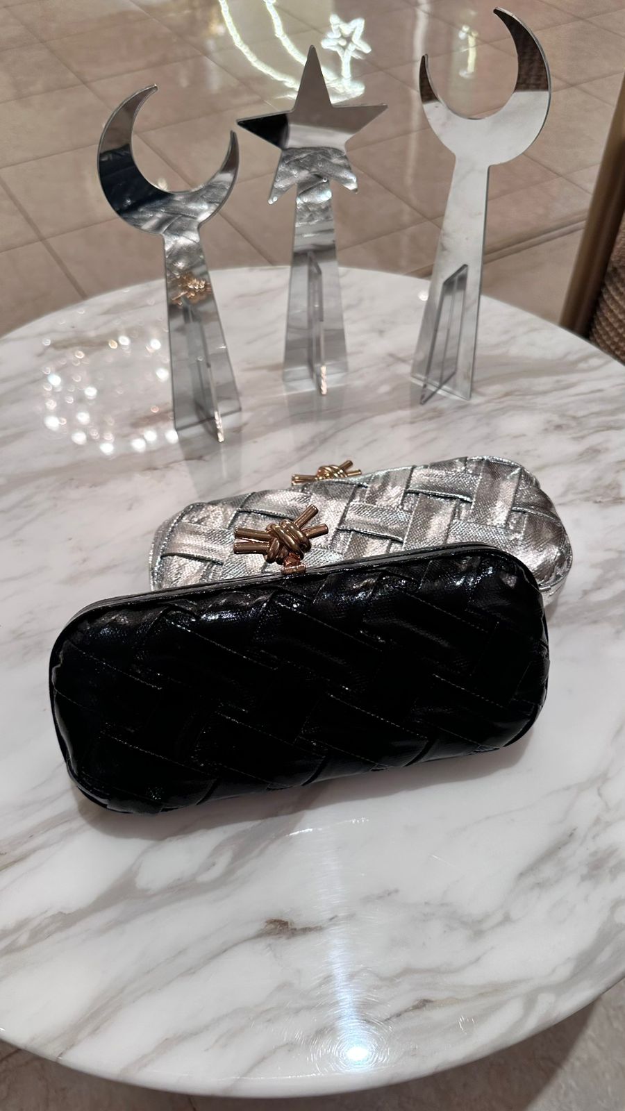Black quilted handbag on a marble surface with decorative metal objects in the background