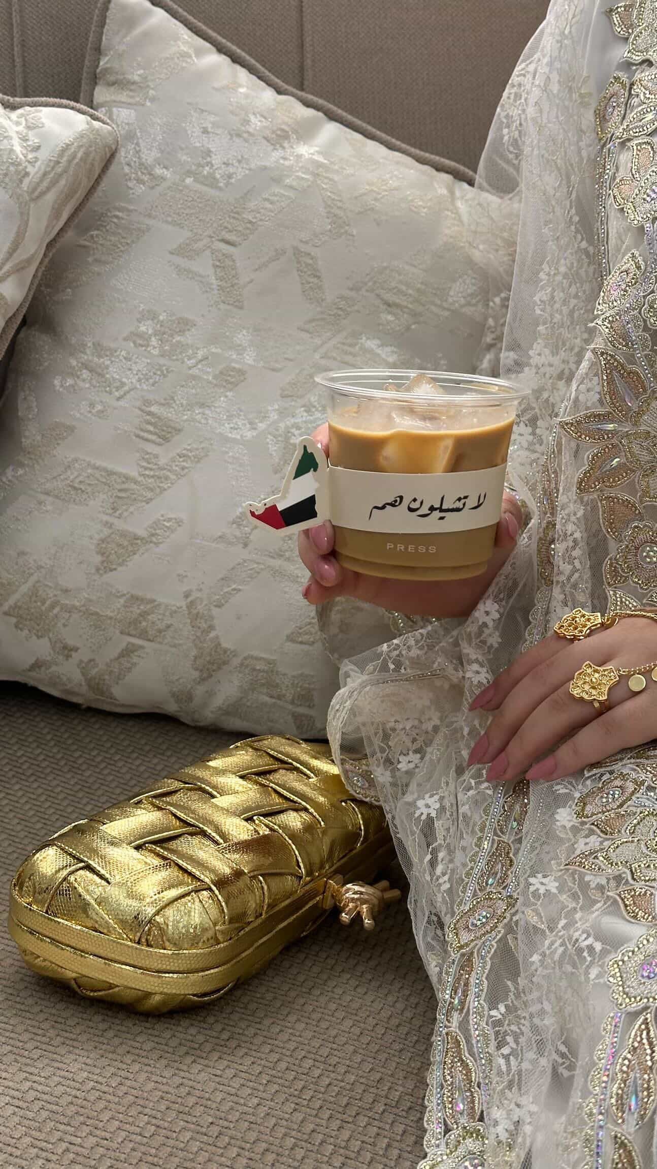 Hand holding a candle with Arabic text on a textured surface