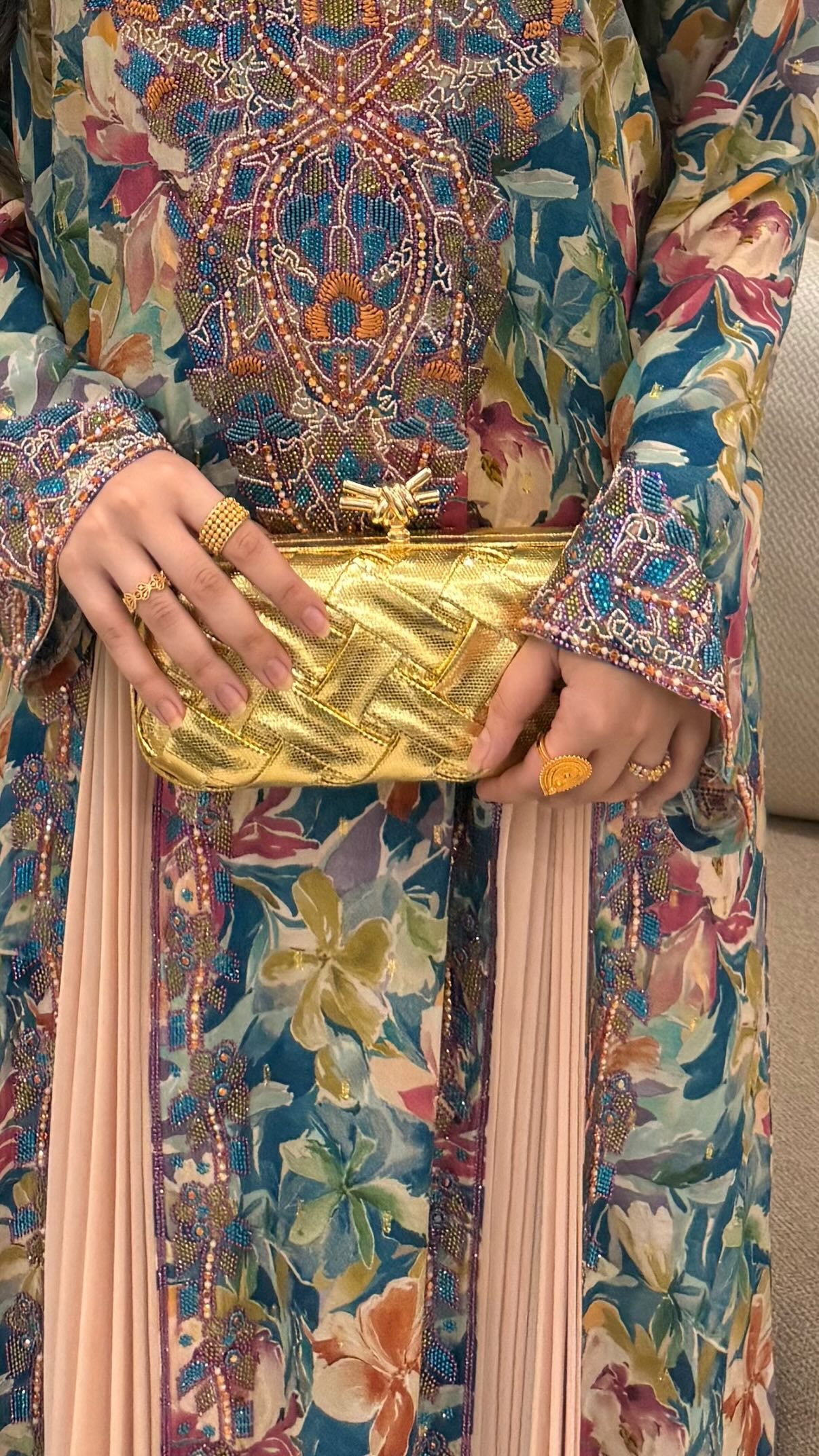 Person holding a gold clutch with a colorful traditional outfit