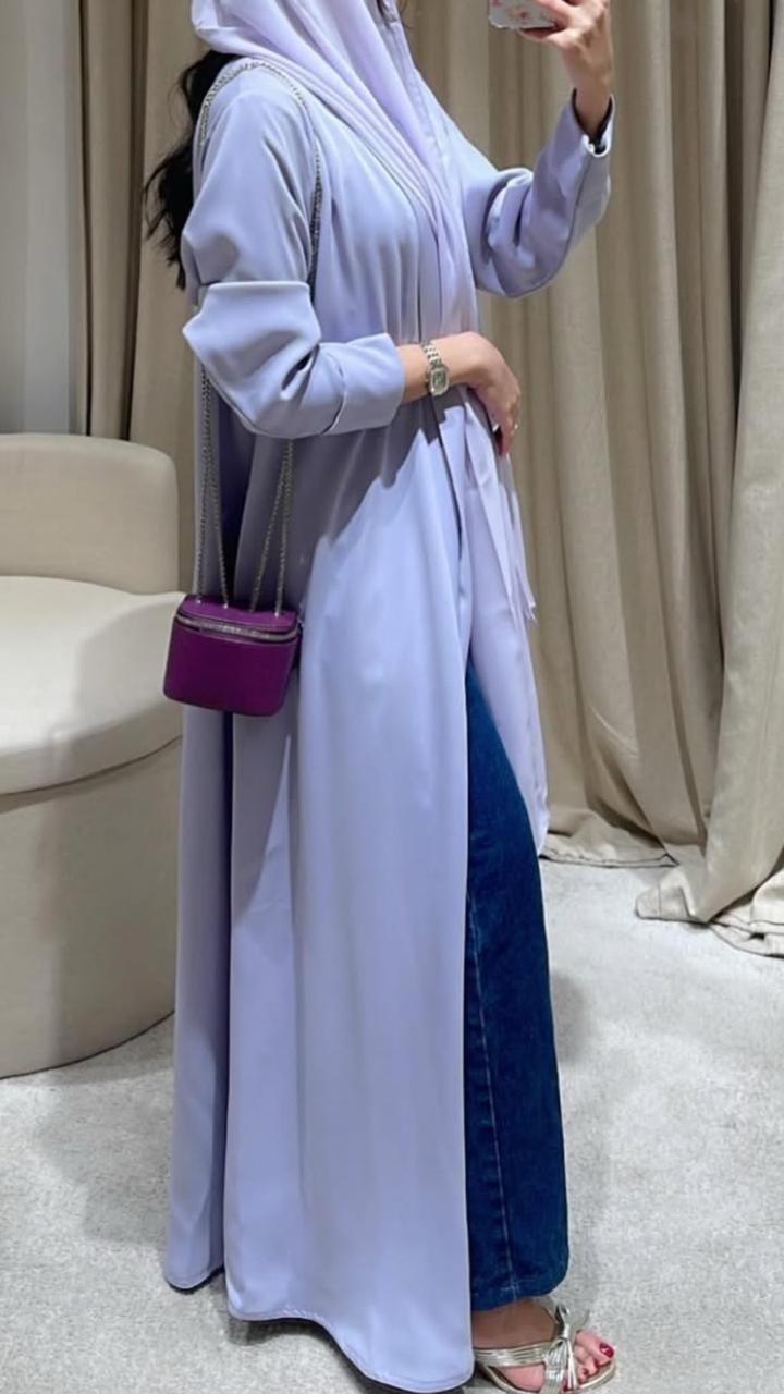 Person wearing a long light blue dress with a purple handbag indoors.