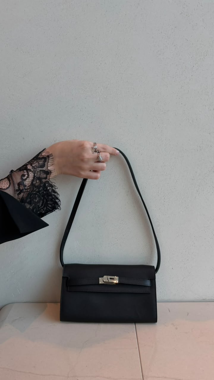 Black clutch bag with shoulder strap held by hand with lace sleeve