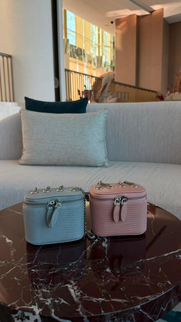 Mini Vanity Chain Bags in pink and blue on marble table with sofa in background