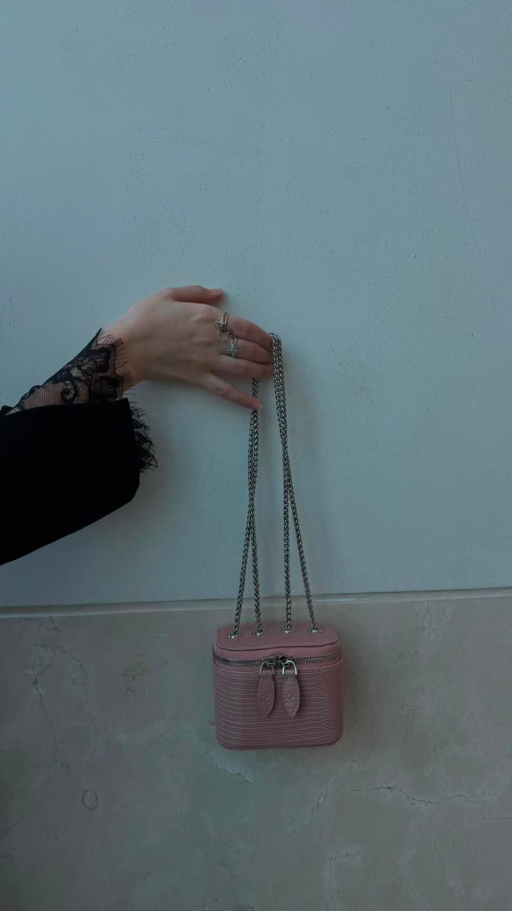 Mini Vanity Chain Bag Pink held by hand with lace sleeve against light blue wall side view