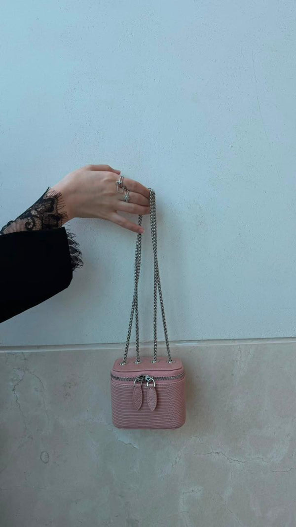 Mini Vanity Chain Bag Pink held by hand with lace sleeve against light blue wall