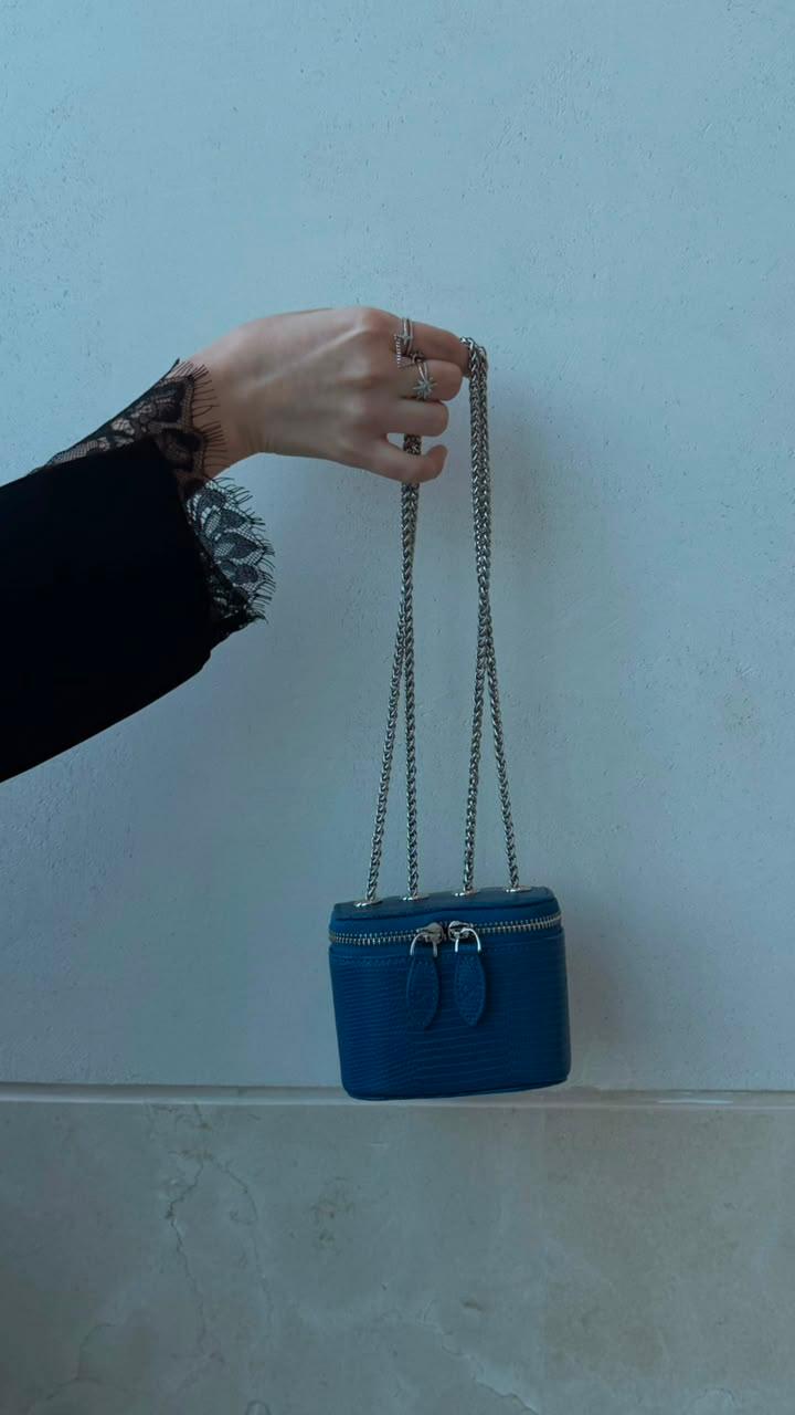 Mini Vanity Chain Bag Royal Blue held by chain strap by hand with black lace sleeve against light wall
