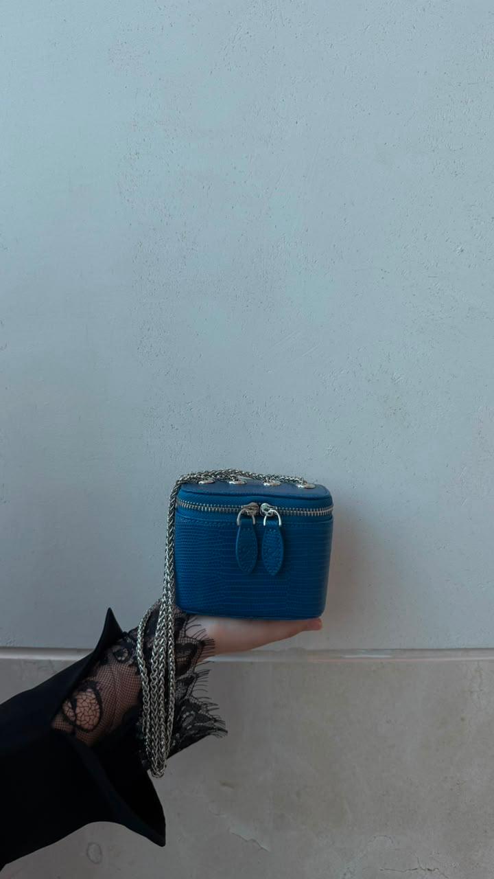 Mini Vanity Chain Bag Royal Blue held in palm of hand with black lace sleeve against light wall