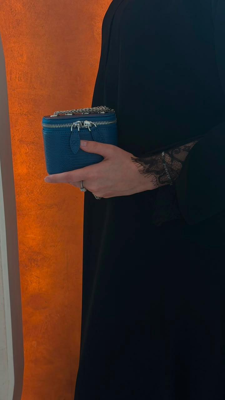 Mini Vanity Chain Bag Royal Blue held in hand against orange wall close up