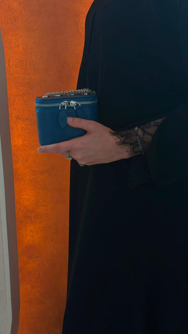 Mini Vanity Chain Bag Royal Blue held in hand against orange wall close up