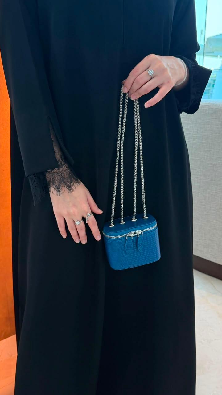 Mini Vanity Chain Bag Royal Blue held by chain strap by woman in black abaya against orange wall front view