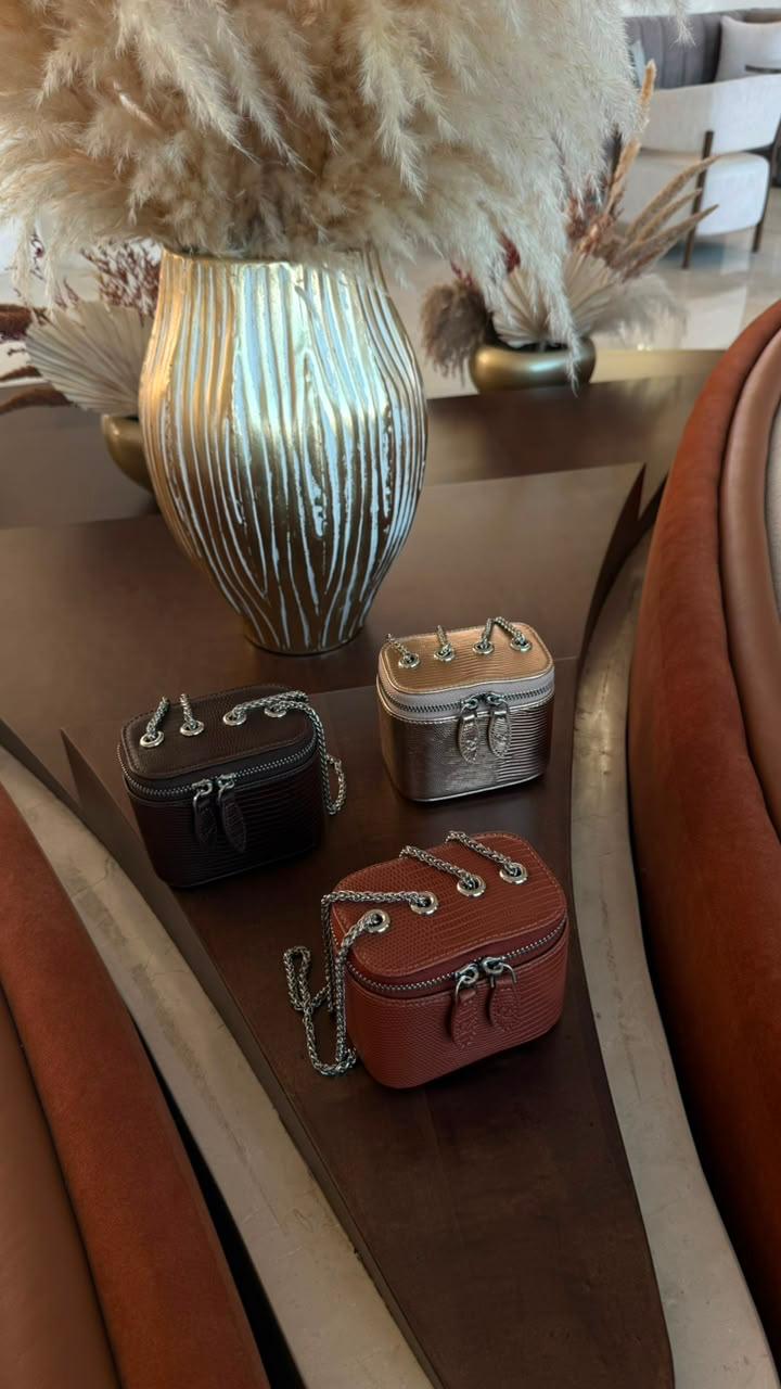 Mini Vanity Chain Bag Espresso held by chain strap by woman in black abaya against orange wall