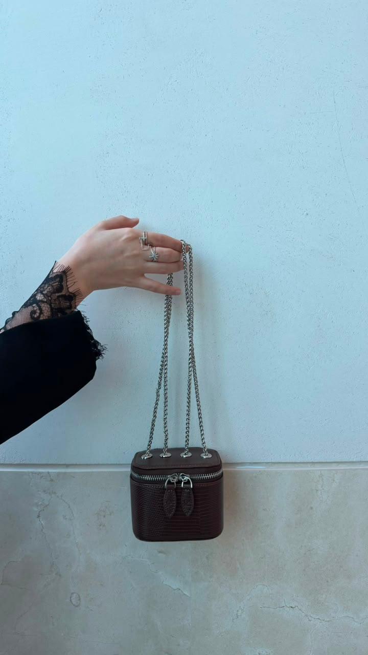 Mini Vanity Chain Bags in black, gold and brown on wooden shelf with pampas grass vase top view