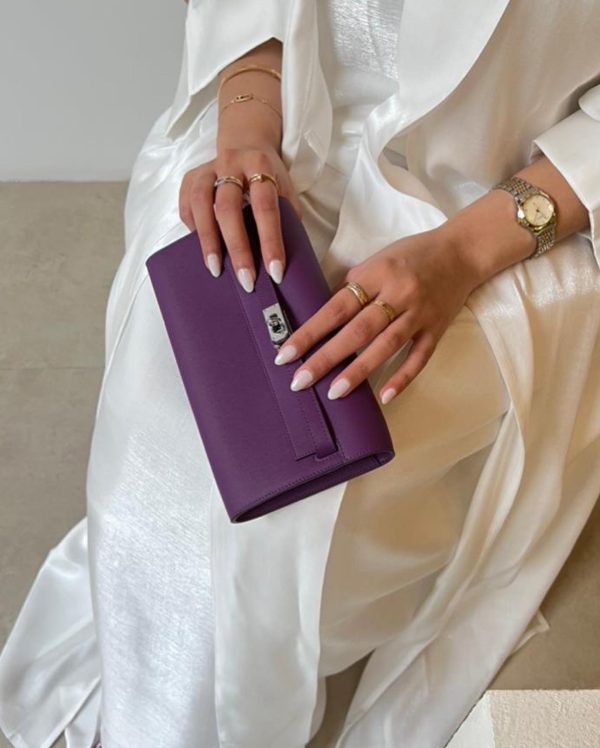 A person holding a purple clutch purse.