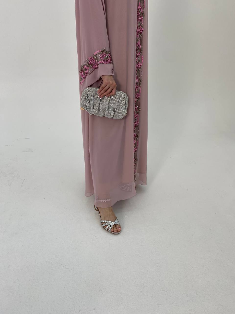 Person wearing a long pink dress with floral details on a white background